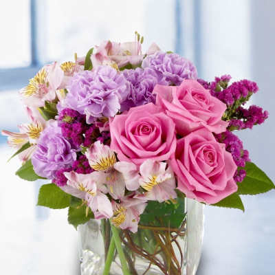 Pink roses and purple carnations in a clear glass vase