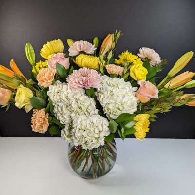 Mixed bouquet of hydrangeas, roses, and chrysanthemums in a glass vase