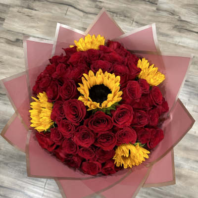 Bouquet of red roses with yellow sunflowers wrapped in pink paper