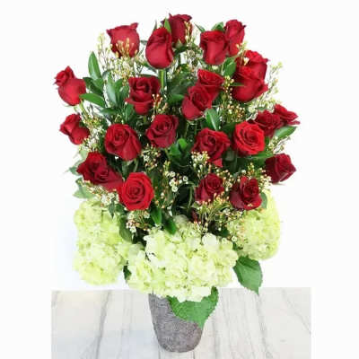 Tall arrangement of red roses with pale green hydrangeas in a textured gray vase