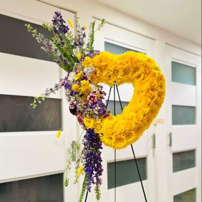 Large yellow floral heart on a black stand with purple flowers cascading down one side