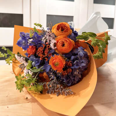 Bouquet of orange and purple flowers wrapped in orange paper