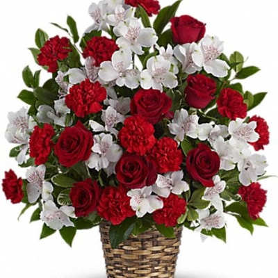 Red roses and carnations with white blossoms in a woven basket