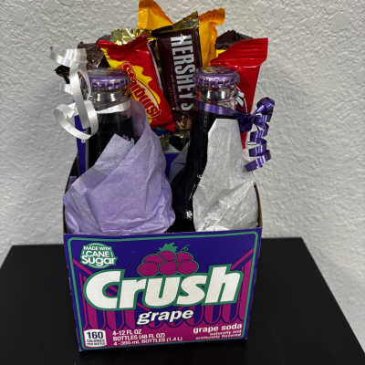 Gift basket with soda bottles and candy bars in a Crush grape box