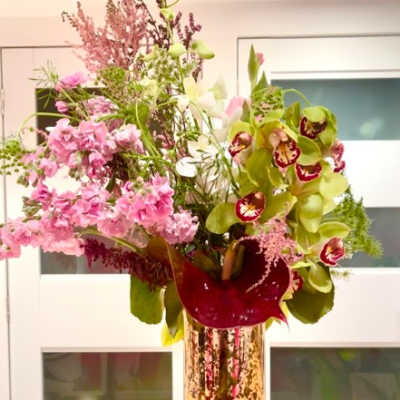 Tall mixed floral arrangement in a glass vase with pink and green blooms
