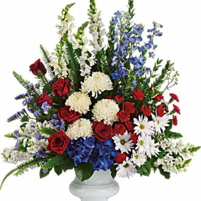 Red roses, white mums, blue flowers, and daisies in a white vase