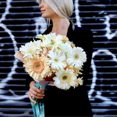 Woman holding a bouquet of pale gerbera daisies