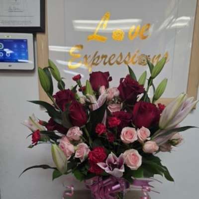 Bouquet of red and pink roses with lilies in a glass vase