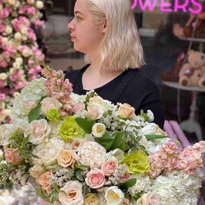 Woman holding a large pastel flower arrangement in a round box