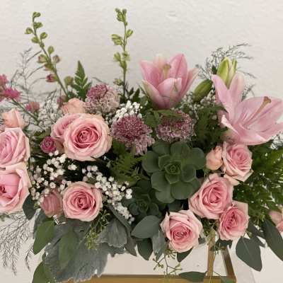 Pink roses and lilies arranged in a low vase with greenery