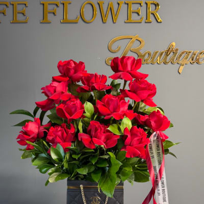 Red rose arrangement in a black box with ribbon accents