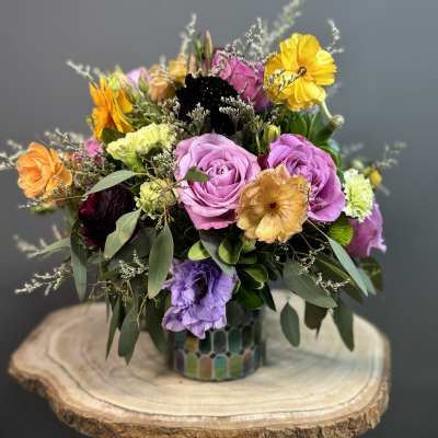 Mixed bouquet of roses and colorful blooms in a patterned vase