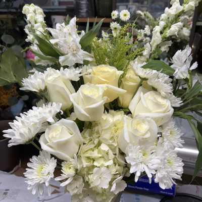 White roses and daisies arranged in a vase with pale hydrangea