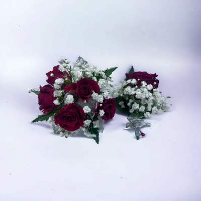 Set of red rose and white filler flower bouquet and matching corsage with silver ribbon on white background