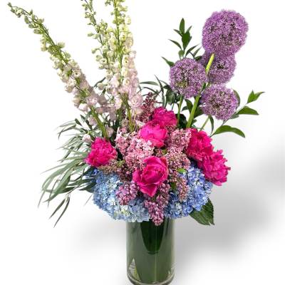 Colorful bouquet of pink, blue, and purple flowers in a glass vase