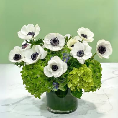 White anemones in a glass vase with bright green hydrangeas