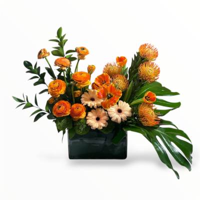 Orange and cream flowers arranged in a dark rectangular vase