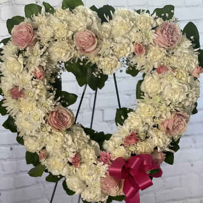 Heart-shaped floral wreath of white and pink flowers with a ribbon bow