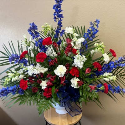 Large red, white, and blue floral arrangement in a white vase