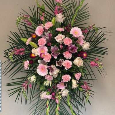 Large pink and white funeral spray with palm fronds
