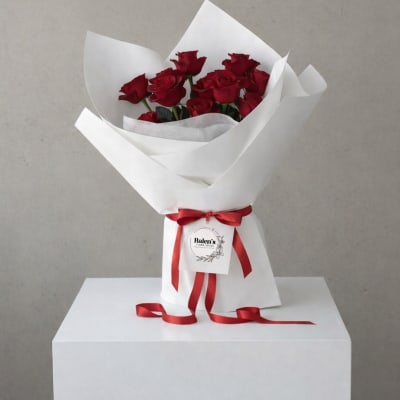 Bouquet of red roses wrapped in white paper with a red ribbon