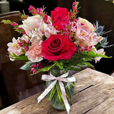 Pink and white flower bouquet in a glass vase with a ribbon