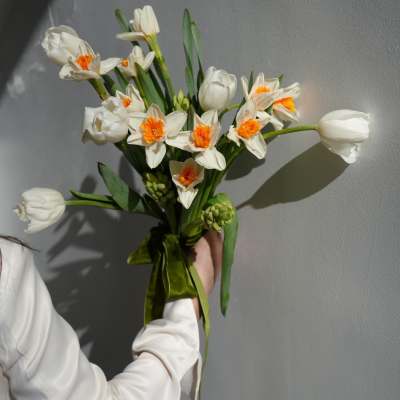 Handheld bouquet of white daffodils with orange centers and white tulips