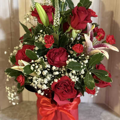 Red roses and white lilies in a red gift box with ribbon