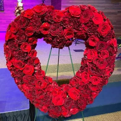 Heart-shaped red rose wreath on a stand