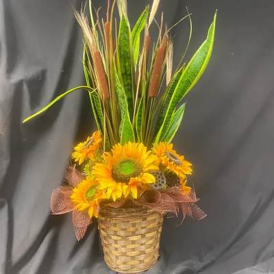 Sunflower arrangement in a woven basket with tall cattails and grasses