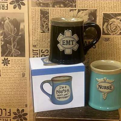 Three novelty mugs with EMT and nurse designs on a shelf