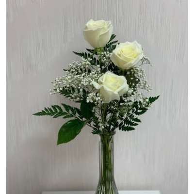 Three white roses in a clear glass vase with baby's breath