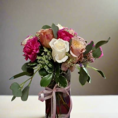 Bouquet of pink and white roses in a glass vase with ribbon
