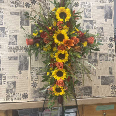 Cross-shaped floral spray with sunflowers, orange roses, and lilies