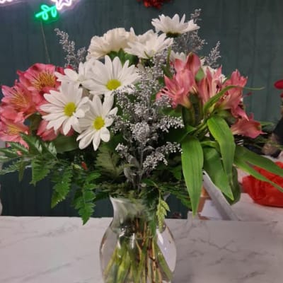 Pink alstroemeria and white daisies in a clear glass vase