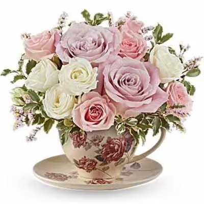 Pink and white roses arranged in a floral teacup and saucer