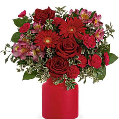 Red roses and pink flowers arranged in a red vase