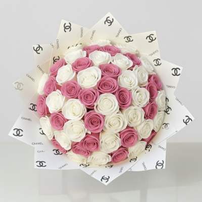Round bouquet of pink and white roses wrapped in Chanel-logo paper