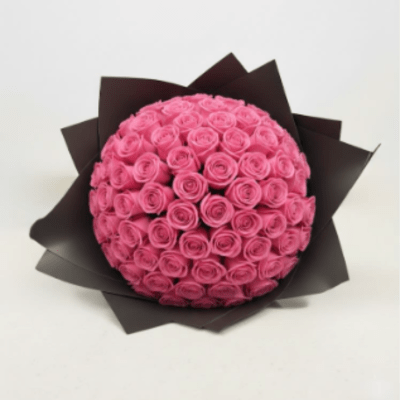 Round bouquet of pink roses wrapped in dark paper
