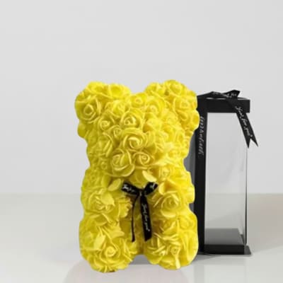 Yellow teddy bear made of roses beside a black gift box