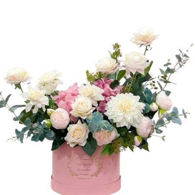 Pink and white floral arrangement in a pink round box