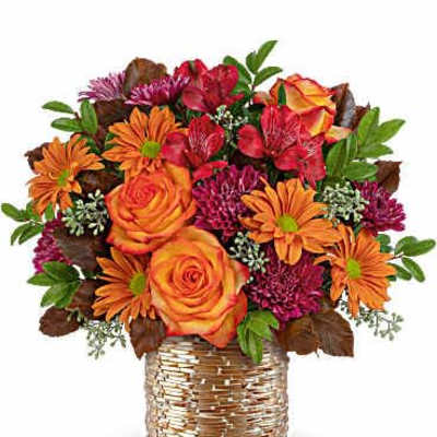 Orange roses and mixed daisies in a woven basket vase