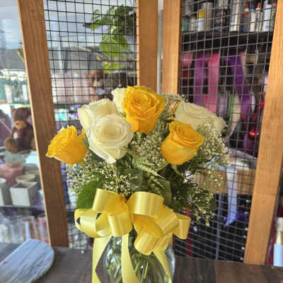 Yellow and white roses in a glass vase with a yellow ribbon
