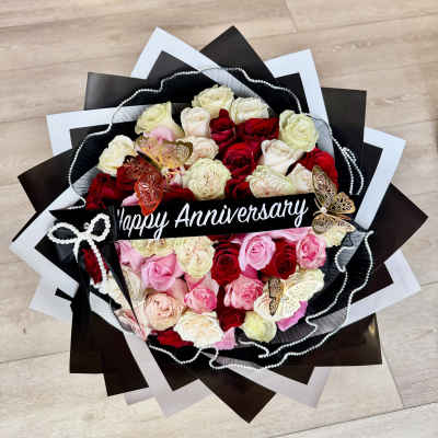 Bouquet of red, pink, and white roses with a Happy Anniversary sign