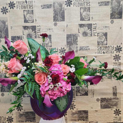 Pink and burgundy floral arrangement in a purple vase