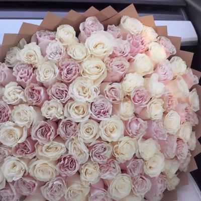 Large bouquet of pale pink and white roses wrapped in brown paper