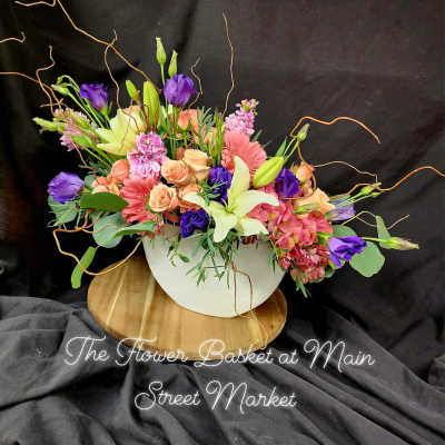 Mixed bouquet in a white bowl vase with pink, purple, and cream flowers