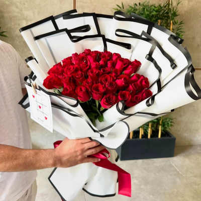 Bouquet of red roses wrapped in white paper with black trim