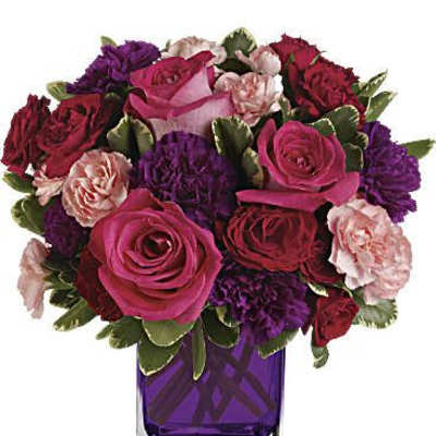 Bouquet of pink, red, and purple roses in a purple glass vase
