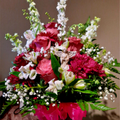 Pink and white mixed flower arrangement with a small angel figurine